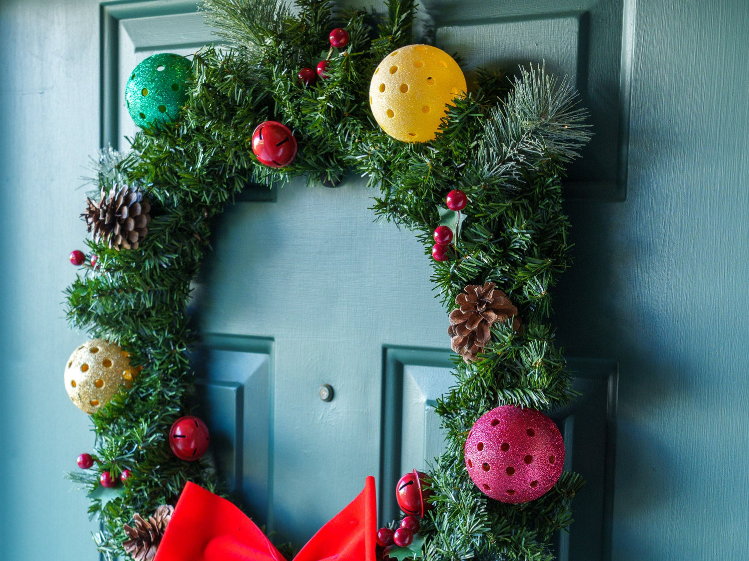 Christmas wreath on a front door with multiple colorful home made pickleball ornaments.