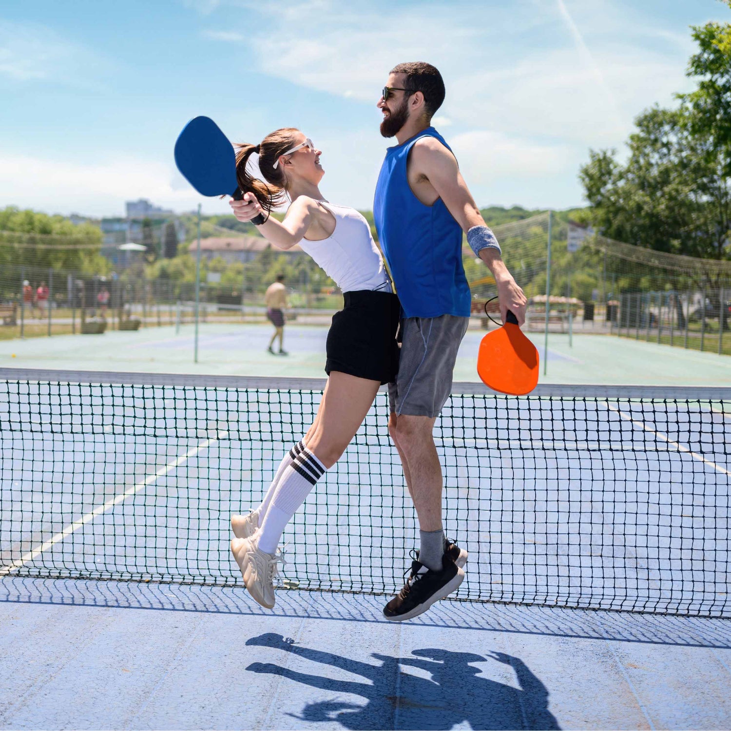 A couple playing pickleball together jumping in the air in excitement