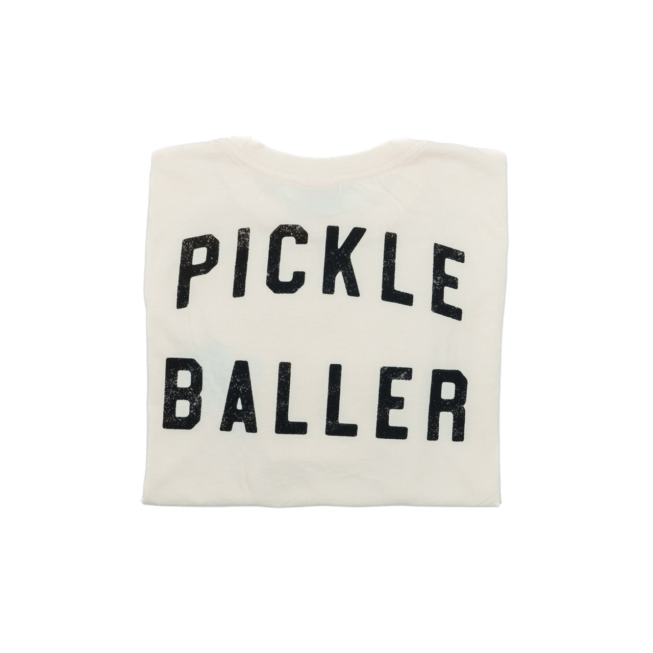 Folded back of cream t-shirt that says "PICKLEBALLER" on the back in black lettering