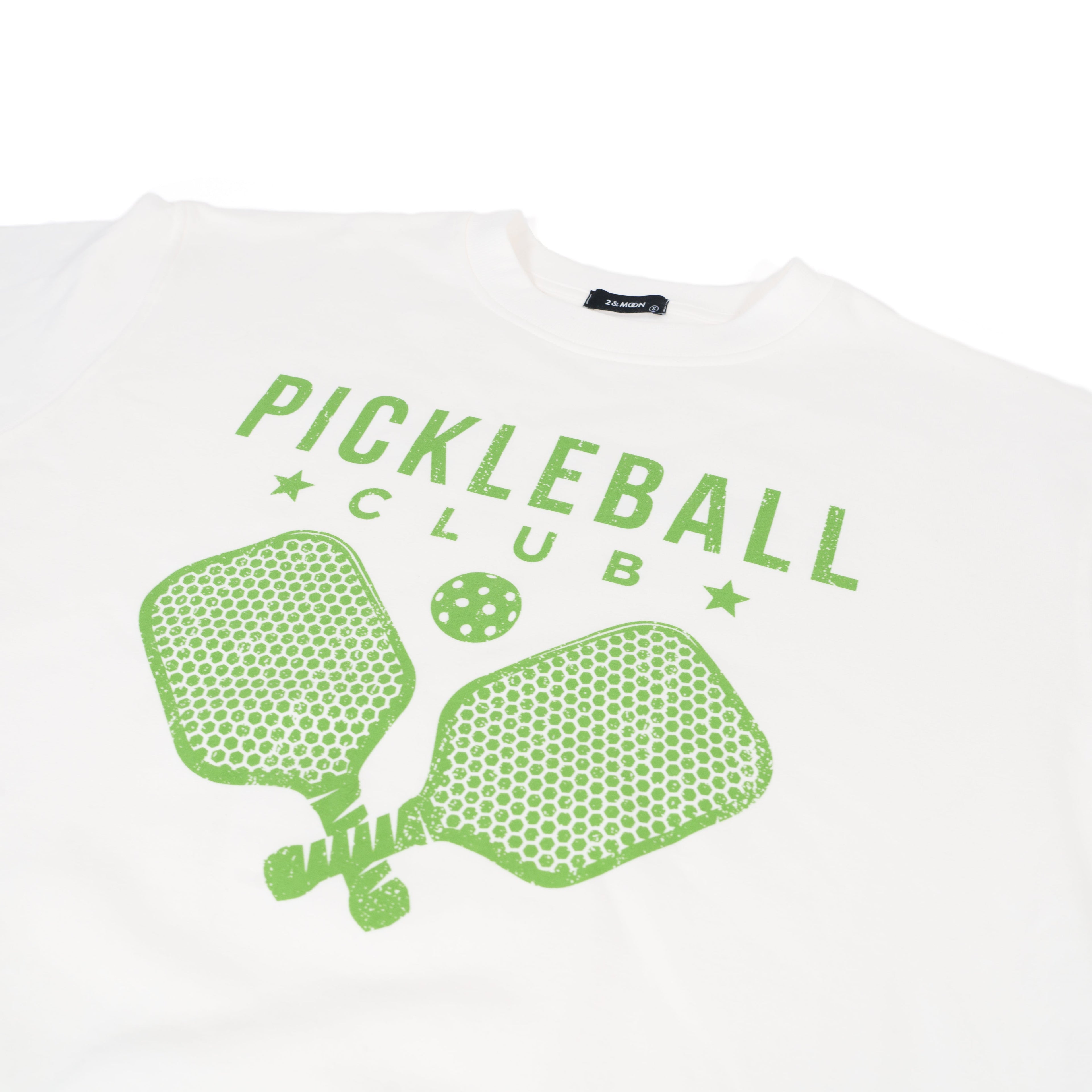 Detailed view of a white crew neck sweatshirt with green text that says "Pickleball Club" and a green image of pickleball paddles and a pickleball on it