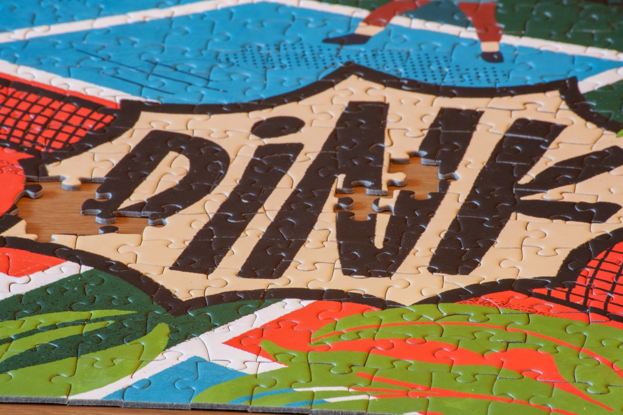 Up close of puzzle pieces that say "DINK" from a 1,000 Piece Pickleball Jigsaw Puzzle
