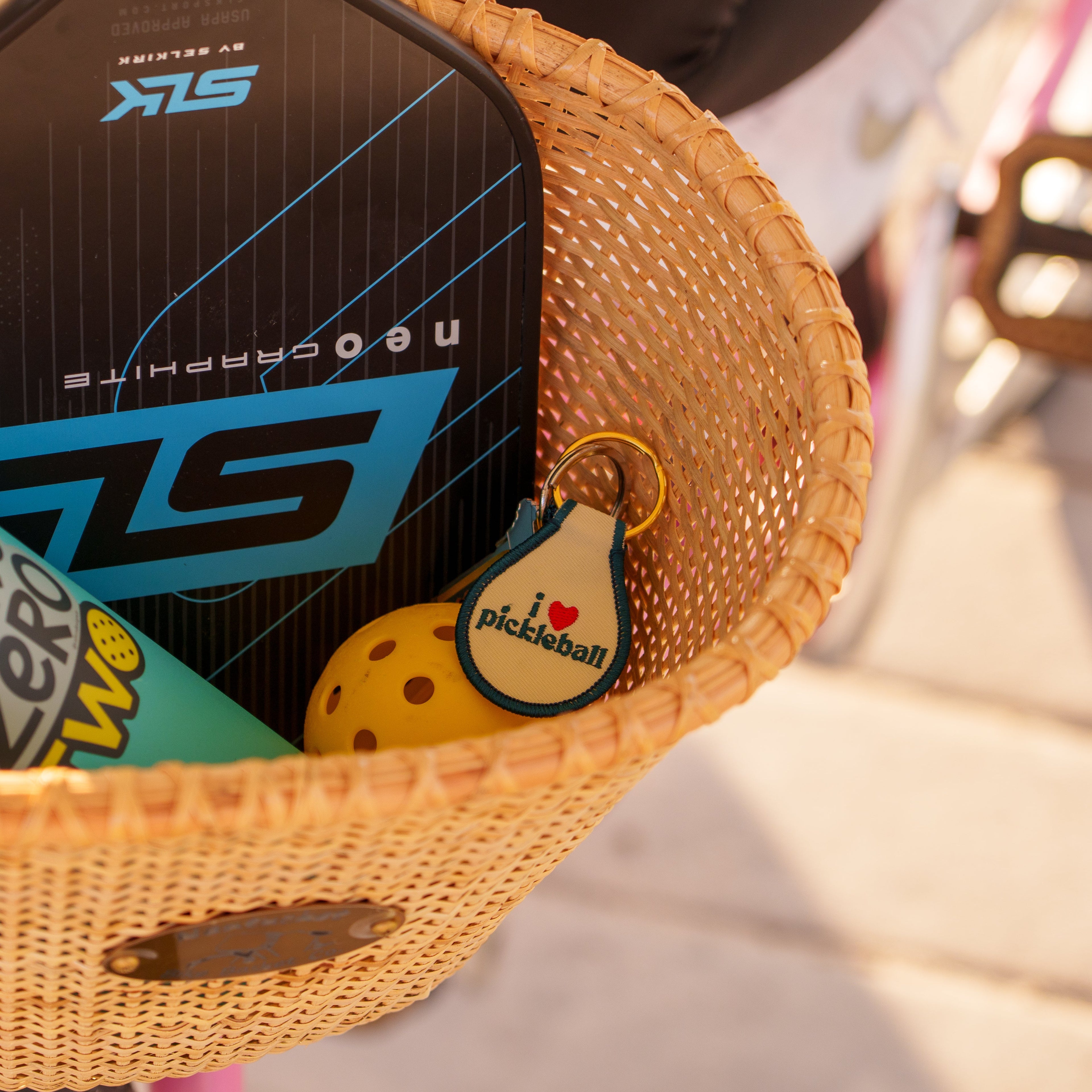 Keychain that says "i heart pickleball" with a pickleball and paddle in a bicycle basket