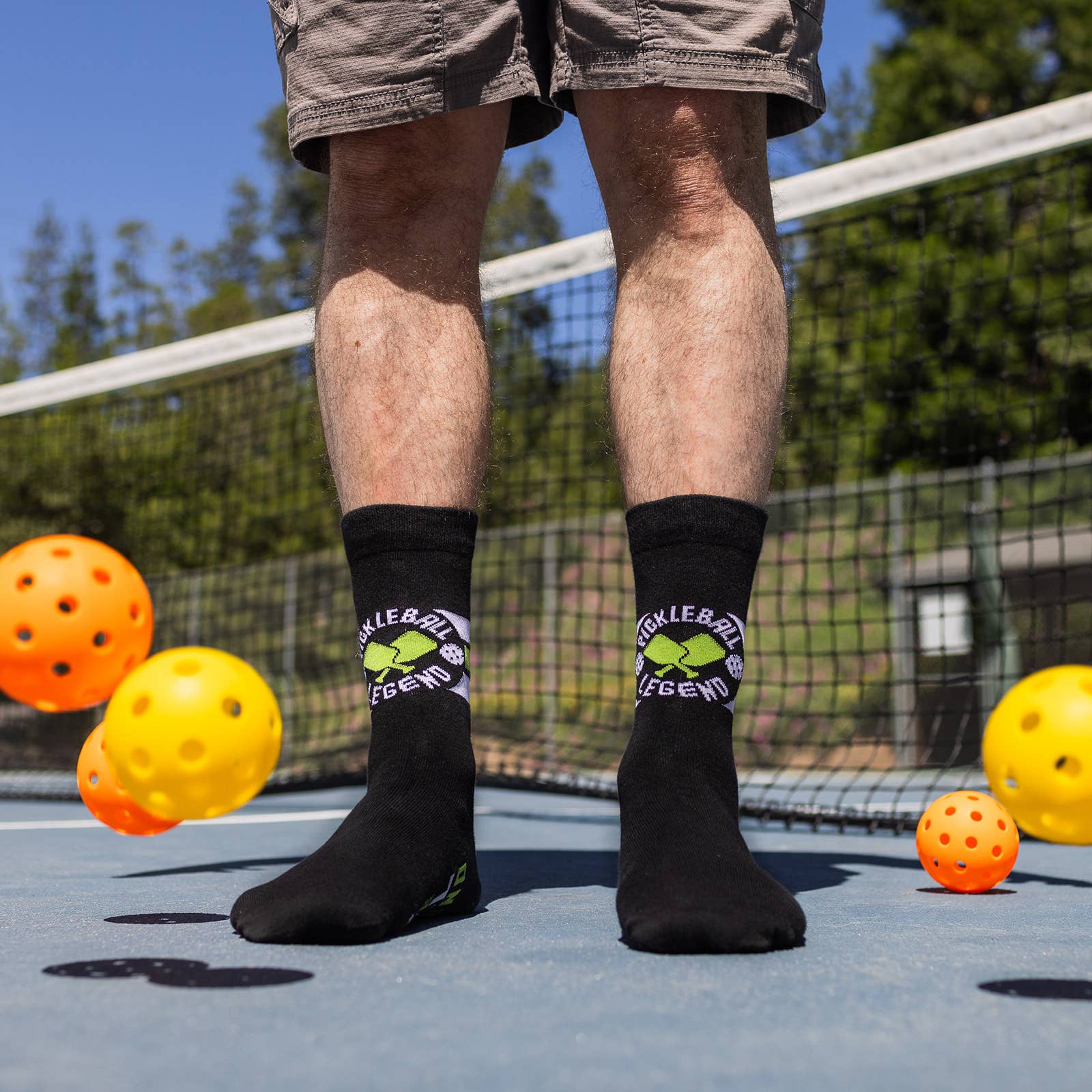 Man standing on a pickleball court with black crew socks that say Pickleball Legend