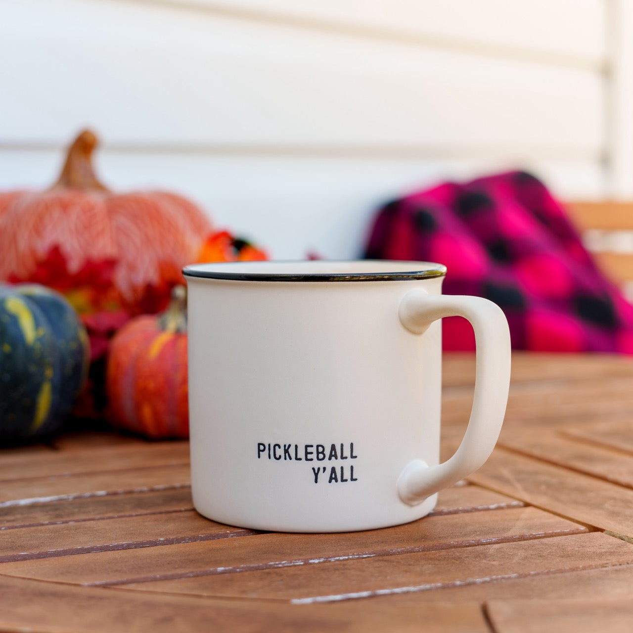 Stoneware coffee mug that says Pickleball Yall on a table in front of pumpkins and a blanket