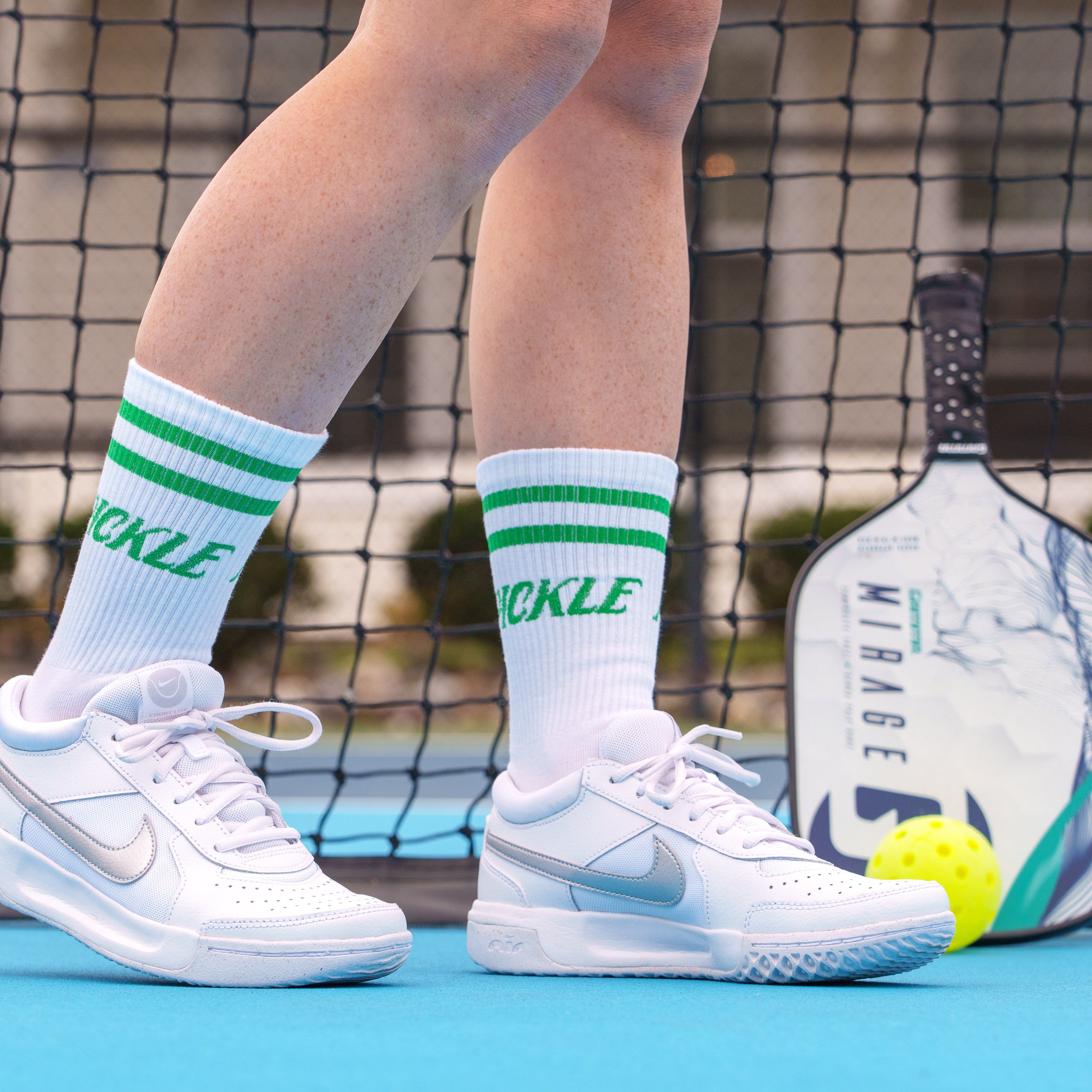 Person wearing retro pickleball cotton spandex mid-calf socks that say "PICKLE" on them on a pickleball court