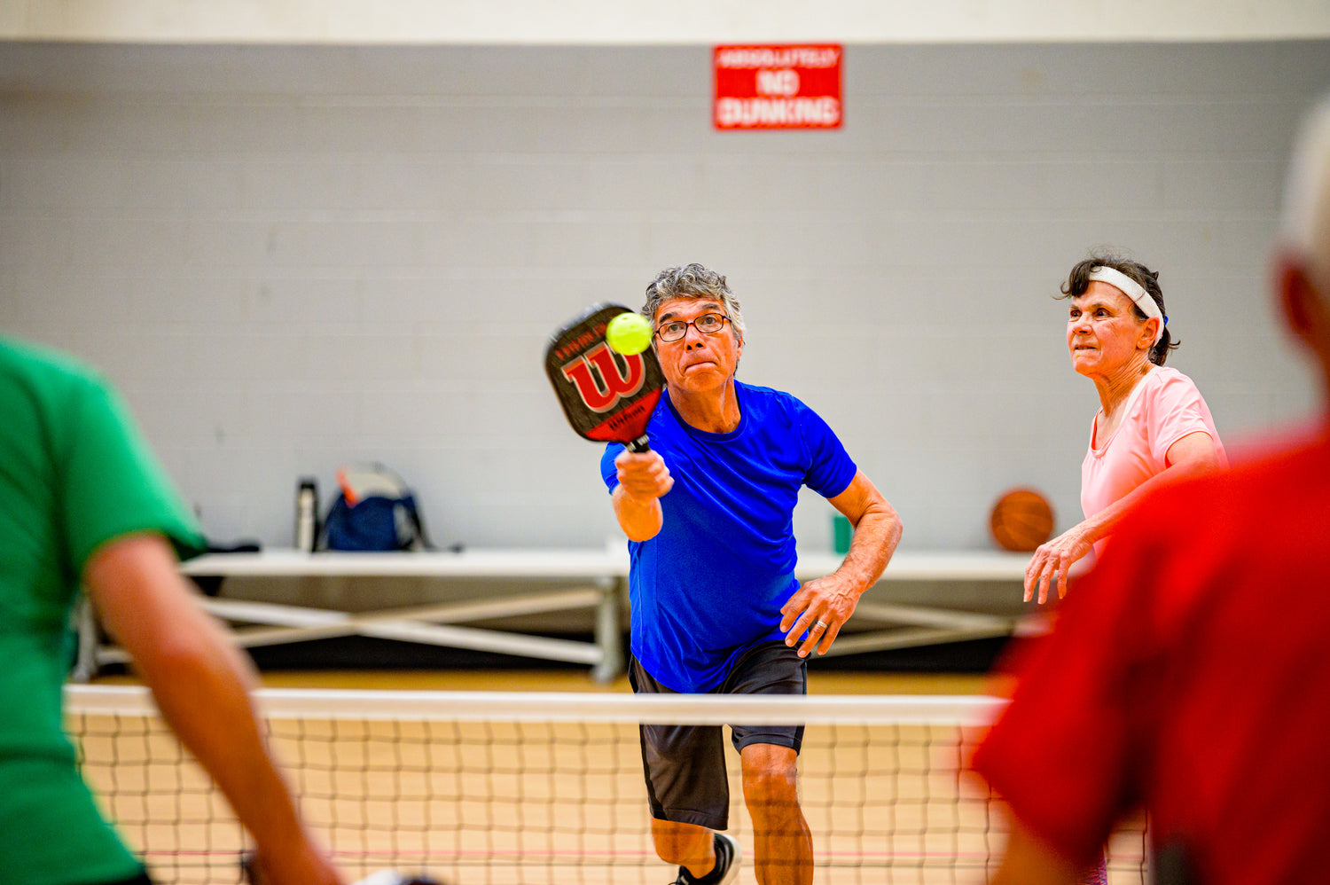 A male pickleball player hitting an overhead smash