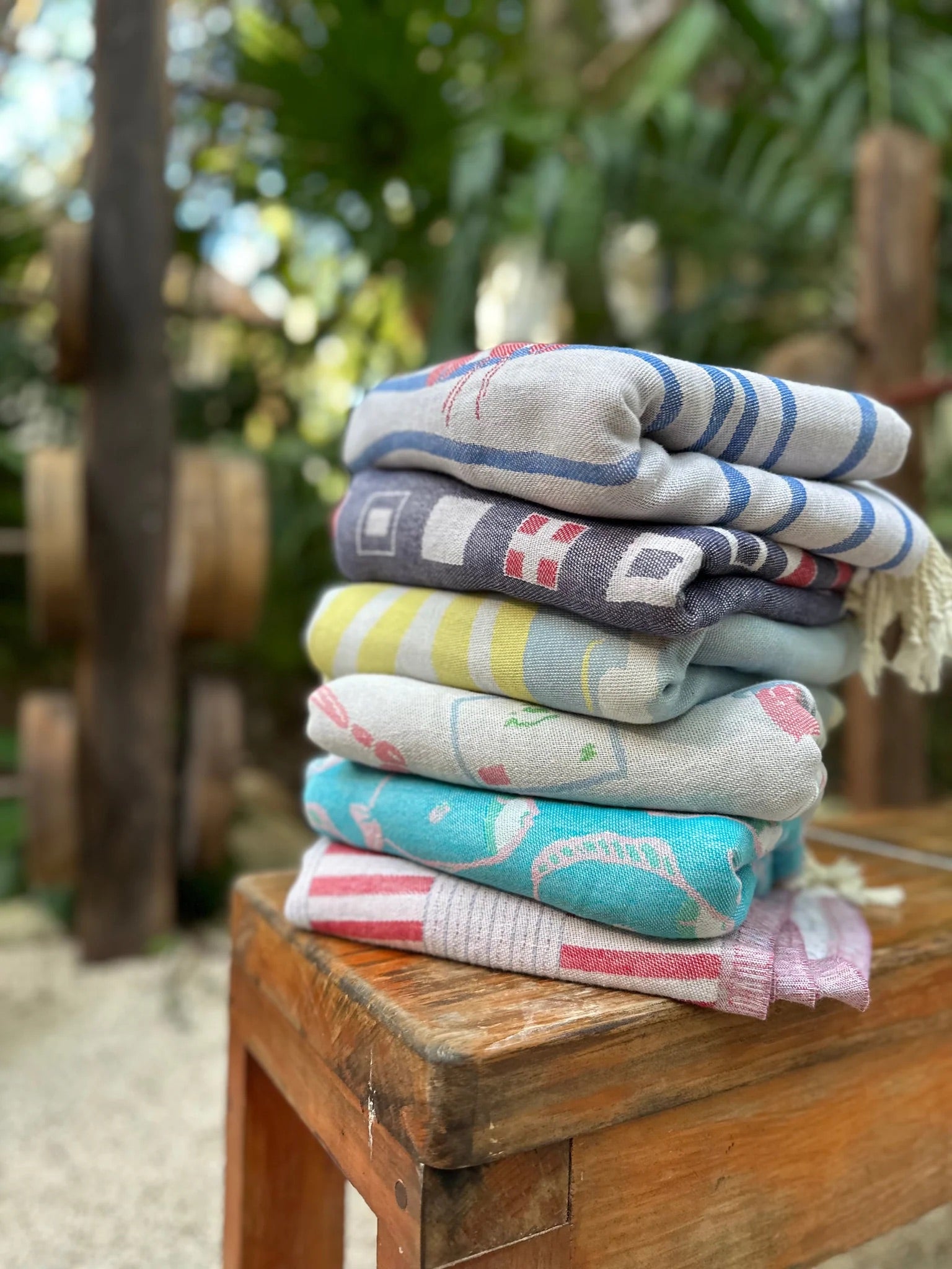 Stack of Turkish beach towels on a table with different themes designed on them like a pickleball court.