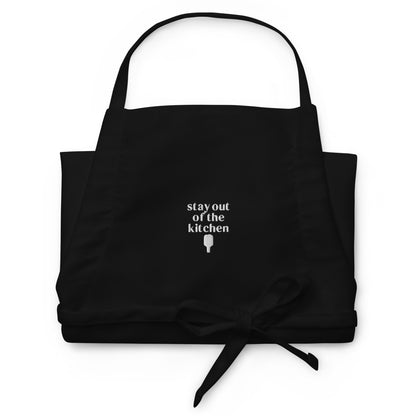 Folded embroidered black apron that says &quot;stay out of the kitchen&quot; and has a pickleball paddle on it