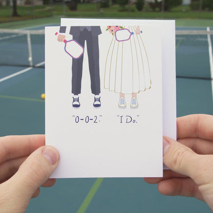 Video of an elegant pickleball themed wedding card with a bride and groom holding pickleball paddles and wearing sneakers