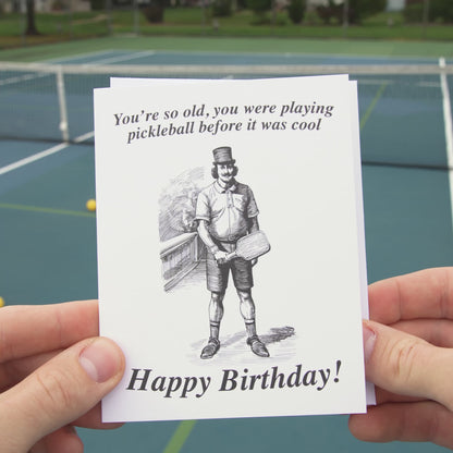Video of a funny pickleball themed birthday card featuring a victorian era man holding an old wooden pickleball paddle.