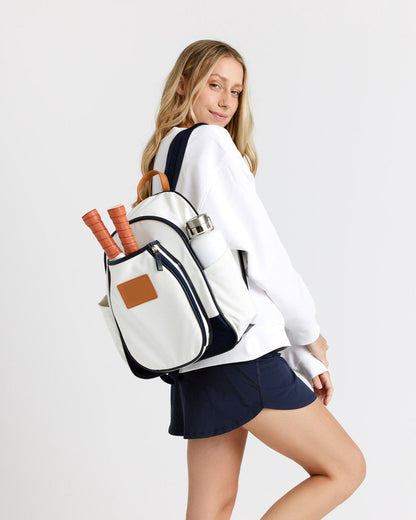 Woman wearing a white and navy blue pickleball backpack with pickleball paddles in it